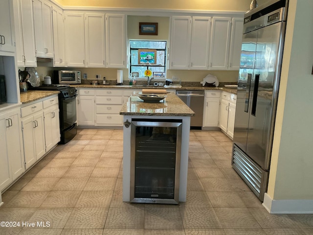 kitchen with white cabinets, light stone countertops, beverage cooler, and appliances with stainless steel finishes