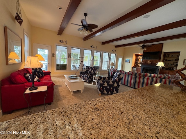 carpeted living room with ceiling fan and beamed ceiling