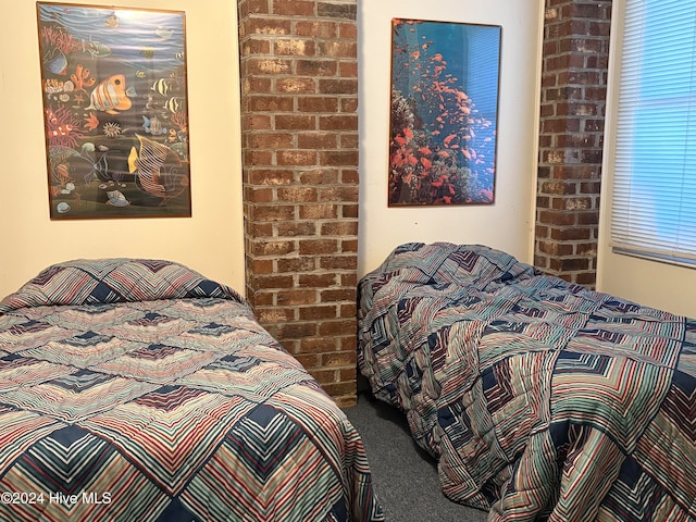 bedroom with multiple windows, carpet flooring, and brick wall