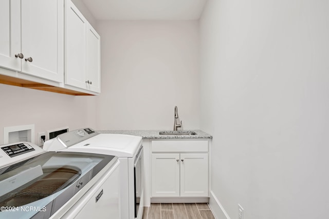 laundry room featuring cabinets, sink, washer and clothes dryer, and light wood-type flooring