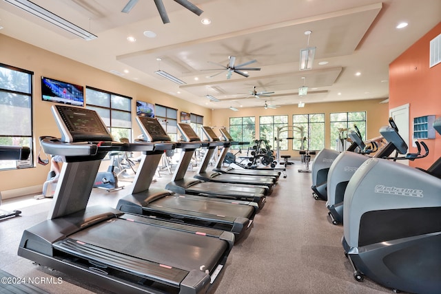 workout area with a tray ceiling and ceiling fan