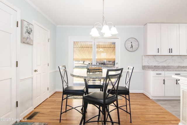 dining room with visible vents, baseboards, a chandelier, ornamental molding, and light wood-style floors