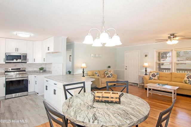 dining area featuring ceiling fan with notable chandelier and light wood finished floors