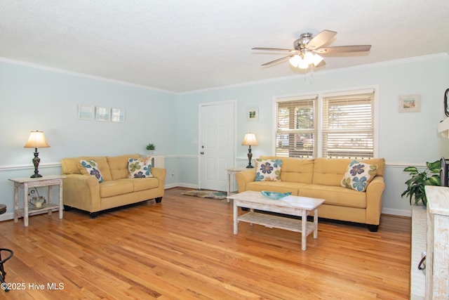 living room featuring light wood-style flooring, baseboards, ceiling fan, and ornamental molding