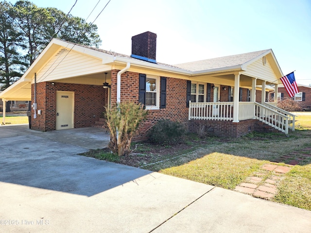 view of front of house featuring brick siding, covered porch, an attached carport, and a chimney