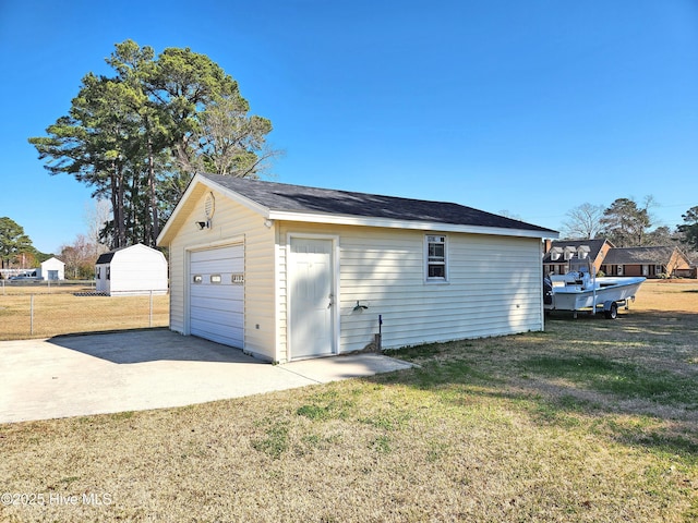 detached garage with concrete driveway and fence