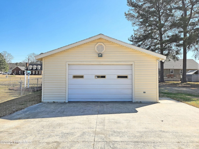 detached garage with concrete driveway and fence