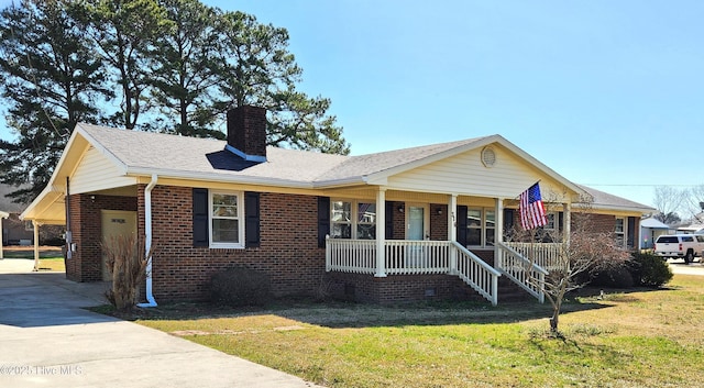 view of front of property with brick siding, a porch, a chimney, and driveway