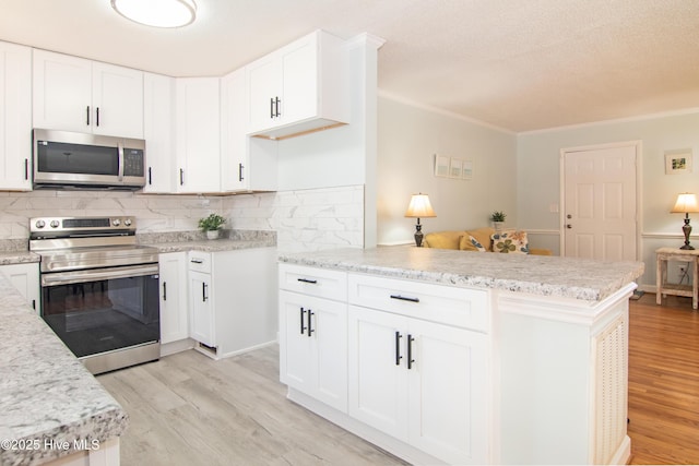 kitchen with white cabinetry, stainless steel appliances, light wood-style floors, a peninsula, and decorative backsplash