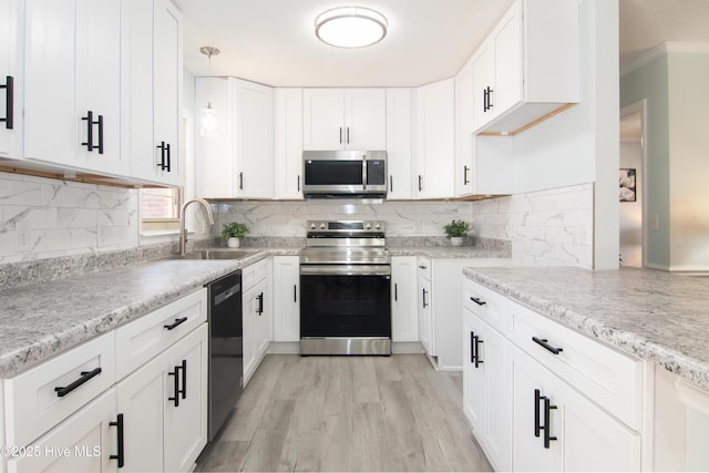 kitchen featuring a sink, stainless steel appliances, white cabinets, and light wood-style flooring