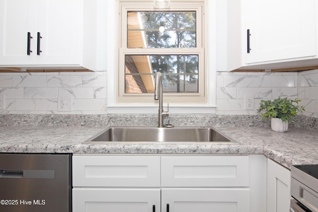 kitchen featuring light countertops, decorative backsplash, white cabinets, stainless steel appliances, and a sink