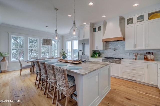 7 S Waterfront Pl, Hampstead, NC 28443 - kitchen featuring appliances with stainless steel finishes, custom range hood, a center island with sink, and white cabinetry