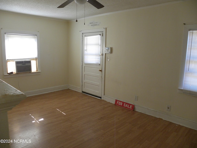 interior space featuring a textured ceiling, cooling unit, hardwood / wood-style floors, ceiling fan, and crown molding