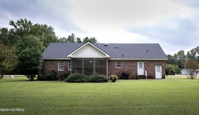 rear view of property featuring a sunroom and a lawn