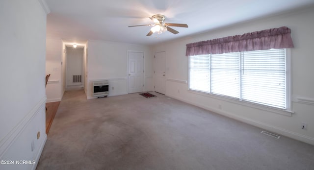 unfurnished living room with crown molding, ceiling fan, carpet, and heating unit