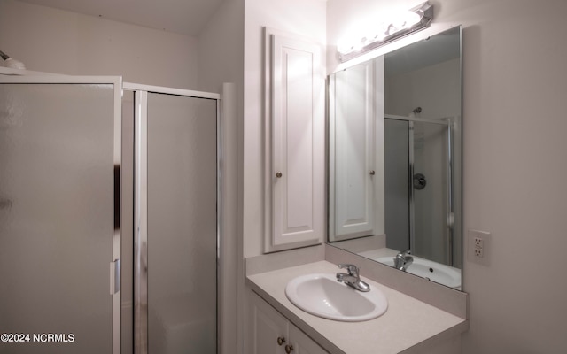 bathroom featuring a shower with door and vanity