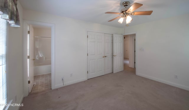 unfurnished bedroom with ceiling fan, ensuite bath, and light carpet