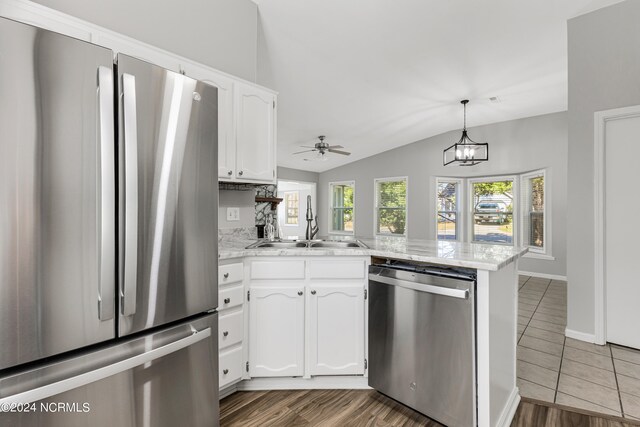 kitchen featuring kitchen peninsula, stainless steel appliances, sink, vaulted ceiling, and white cabinetry