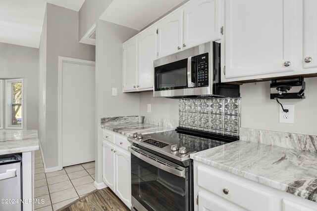 kitchen featuring white cabinetry, light stone counters, appliances with stainless steel finishes, and light tile patterned floors