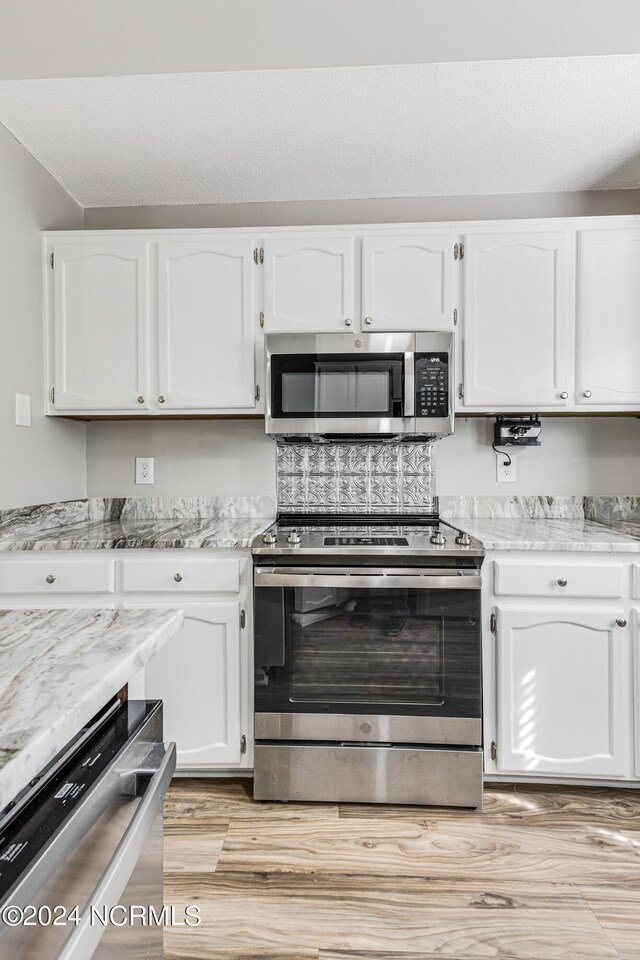 kitchen featuring light stone countertops, light hardwood / wood-style floors, appliances with stainless steel finishes, and white cabinets