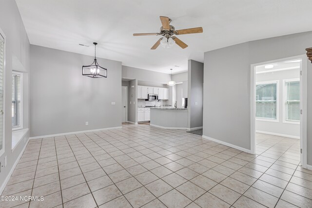 unfurnished living room featuring light tile patterned flooring and ceiling fan with notable chandelier