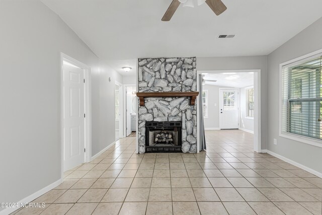 unfurnished living room featuring ceiling fan, a stone fireplace, lofted ceiling, and light tile patterned floors