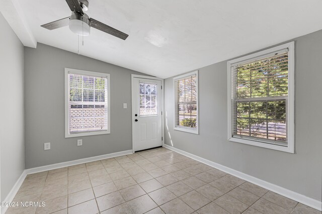 tiled empty room with vaulted ceiling, a wealth of natural light, and ceiling fan