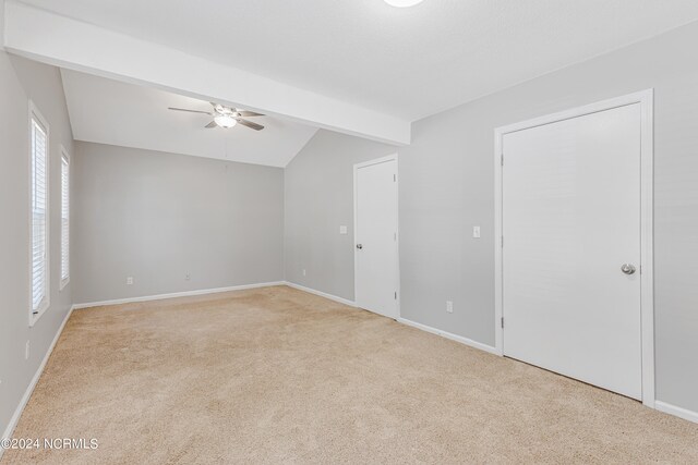 interior space featuring vaulted ceiling with beams, light colored carpet, and ceiling fan