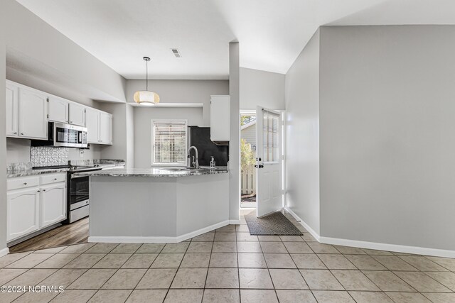 kitchen featuring light tile patterned floors, appliances with stainless steel finishes, white cabinetry, pendant lighting, and light stone counters