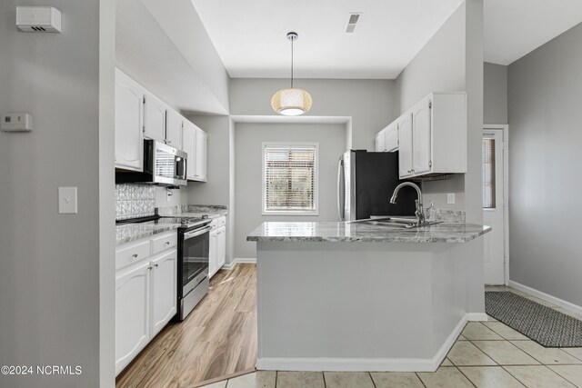 kitchen with kitchen peninsula, hanging light fixtures, white cabinetry, stainless steel appliances, and light tile patterned floors