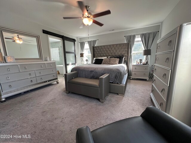 carpeted bedroom with a barn door and ceiling fan