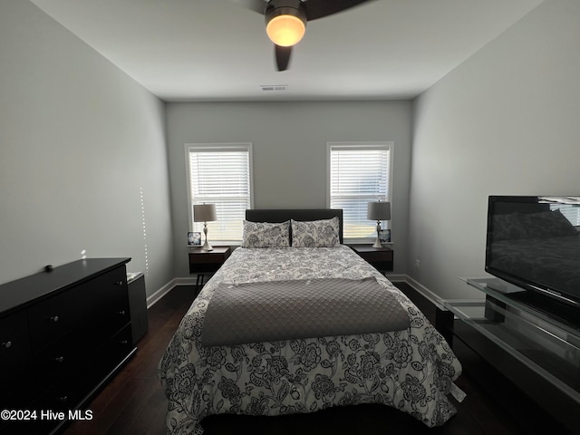 bedroom featuring ceiling fan, multiple windows, and dark hardwood / wood-style flooring