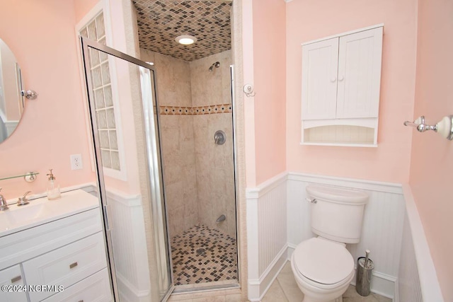 bathroom featuring vanity, toilet, tile patterned flooring, and a shower with door