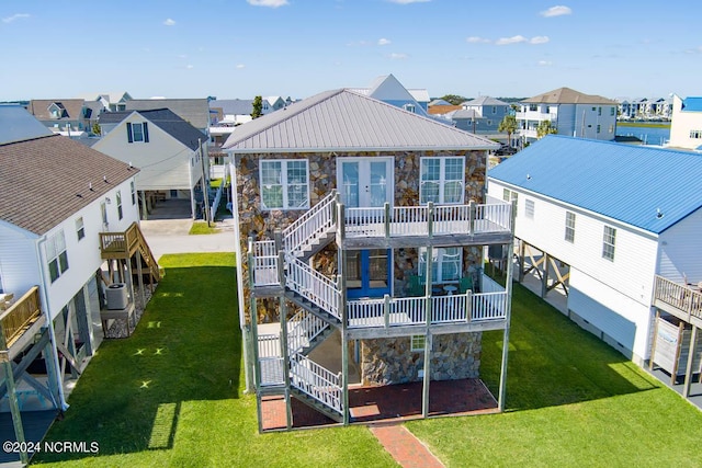 rear view of property featuring french doors, a balcony, and a lawn