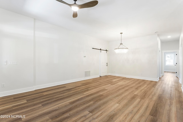 spare room with hardwood / wood-style floors, ceiling fan, and a barn door