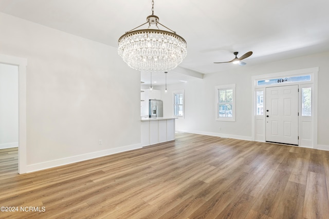 entryway with ceiling fan with notable chandelier and light wood-type flooring