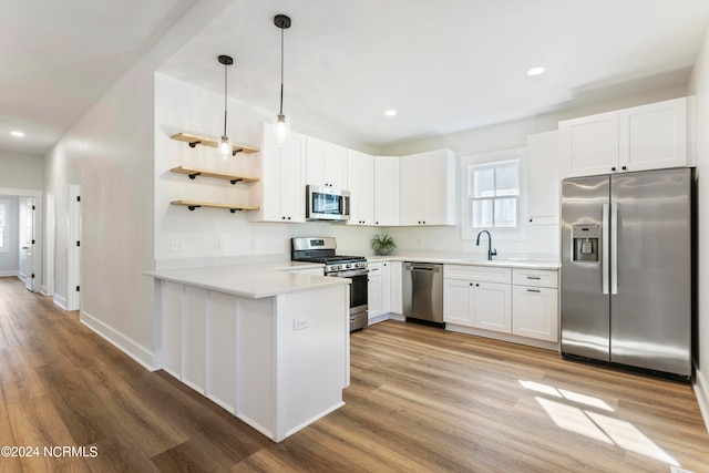 kitchen with kitchen peninsula, light wood-type flooring, stainless steel appliances, and white cabinetry