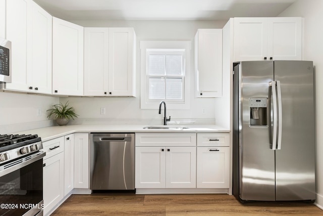 kitchen with hardwood / wood-style flooring, sink, white cabinets, and appliances with stainless steel finishes