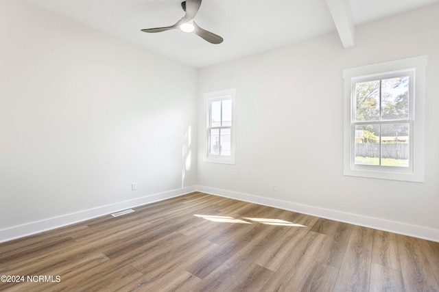 spare room featuring beam ceiling, ceiling fan, and light wood-type flooring