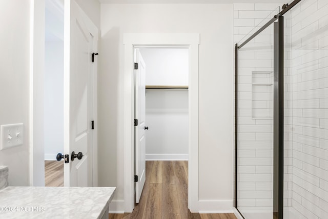 bathroom with vanity, a shower with shower door, and wood-type flooring