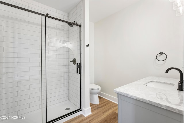 bathroom featuring hardwood / wood-style floors, vanity, toilet, and a shower with shower door