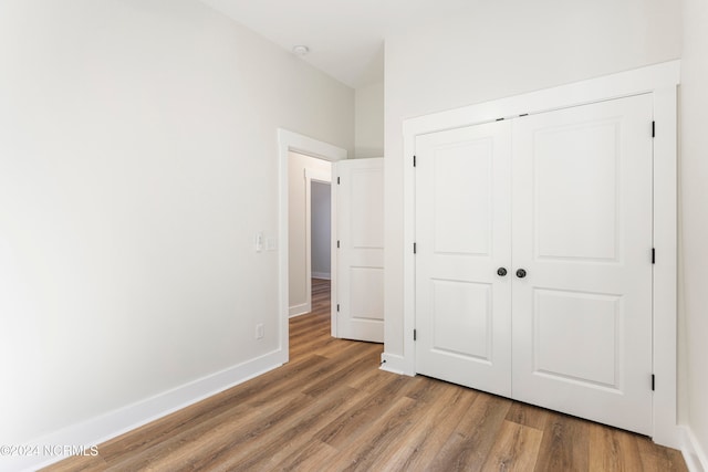 unfurnished bedroom with wood-type flooring and a closet