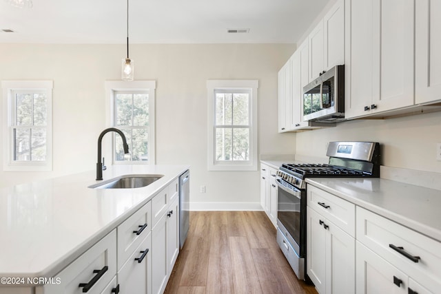 kitchen featuring sink, white cabinets, light hardwood / wood-style floors, and appliances with stainless steel finishes