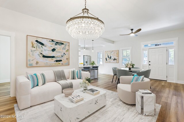 living room featuring ceiling fan with notable chandelier and light hardwood / wood-style flooring