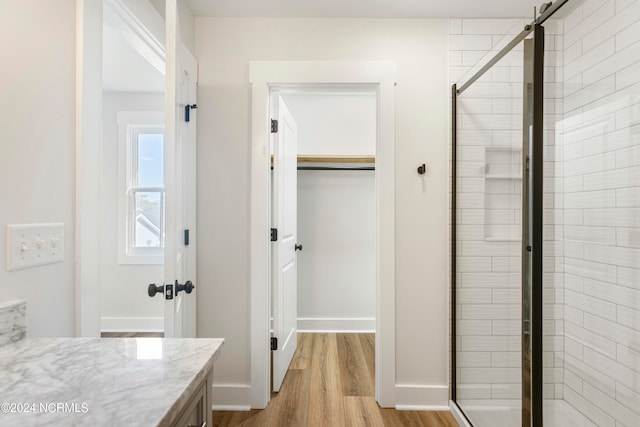 bathroom with hardwood / wood-style floors, vanity, and a shower with door