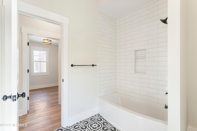 bathroom featuring wood-type flooring and tiled shower / bath