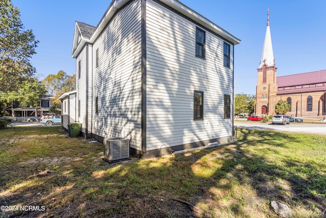 view of side of property featuring a lawn and central AC