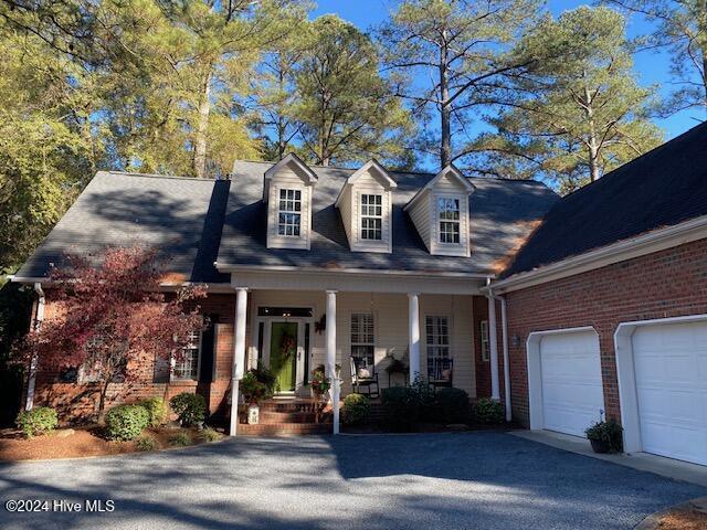 new england style home featuring a garage and covered porch