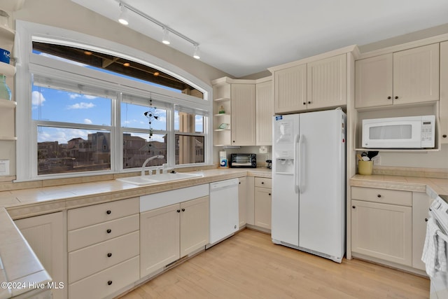 kitchen featuring sink, light hardwood / wood-style flooring, tile counters, white appliances, and cream cabinetry