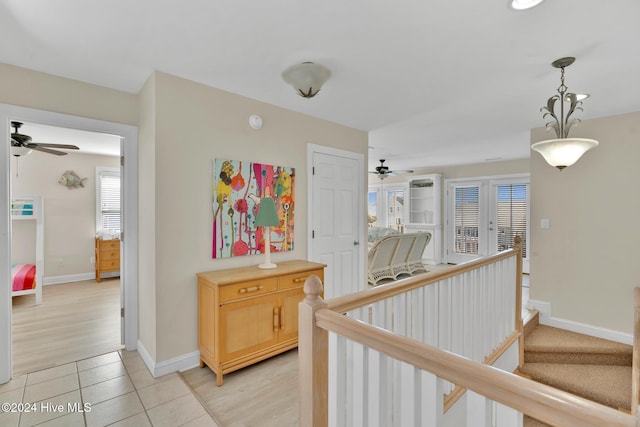 hallway featuring french doors, a healthy amount of sunlight, and light tile patterned flooring